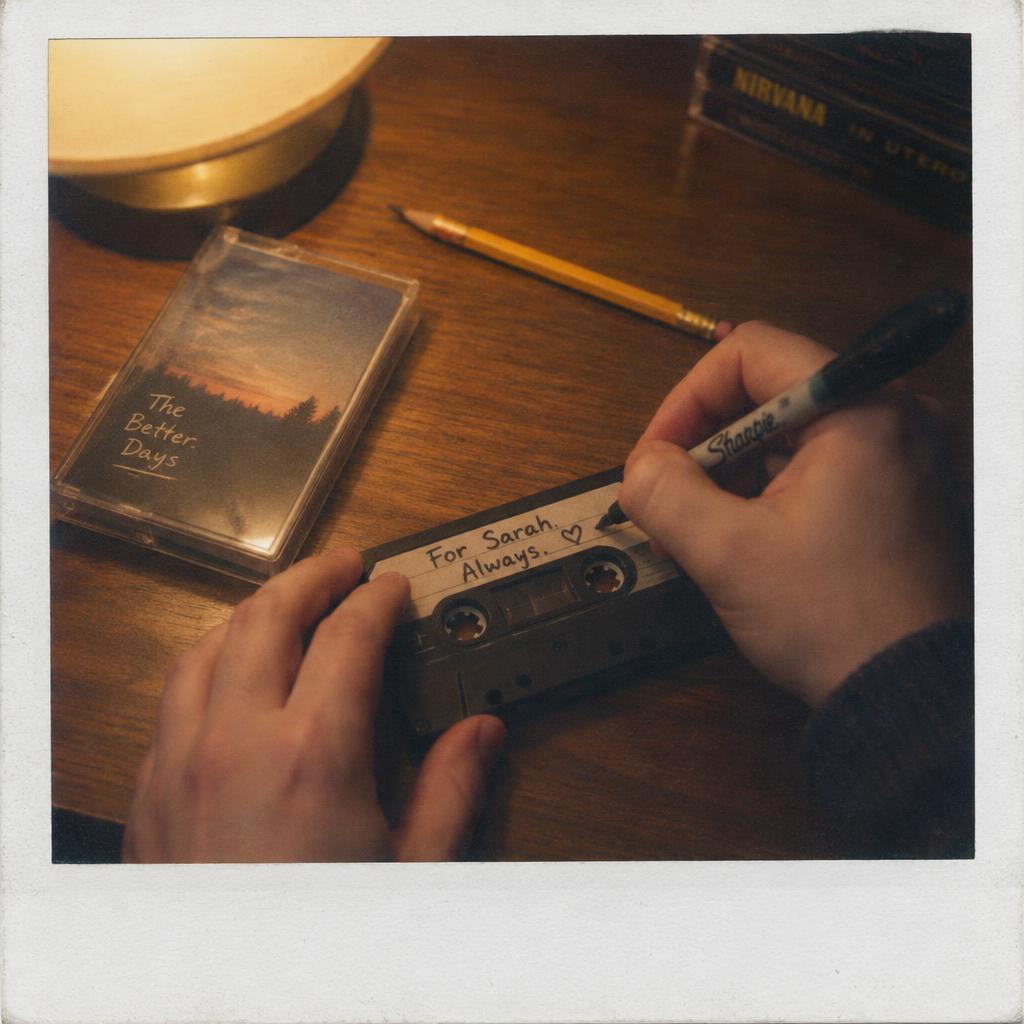 Hands writing a dedication on a cassette label with a sharpie